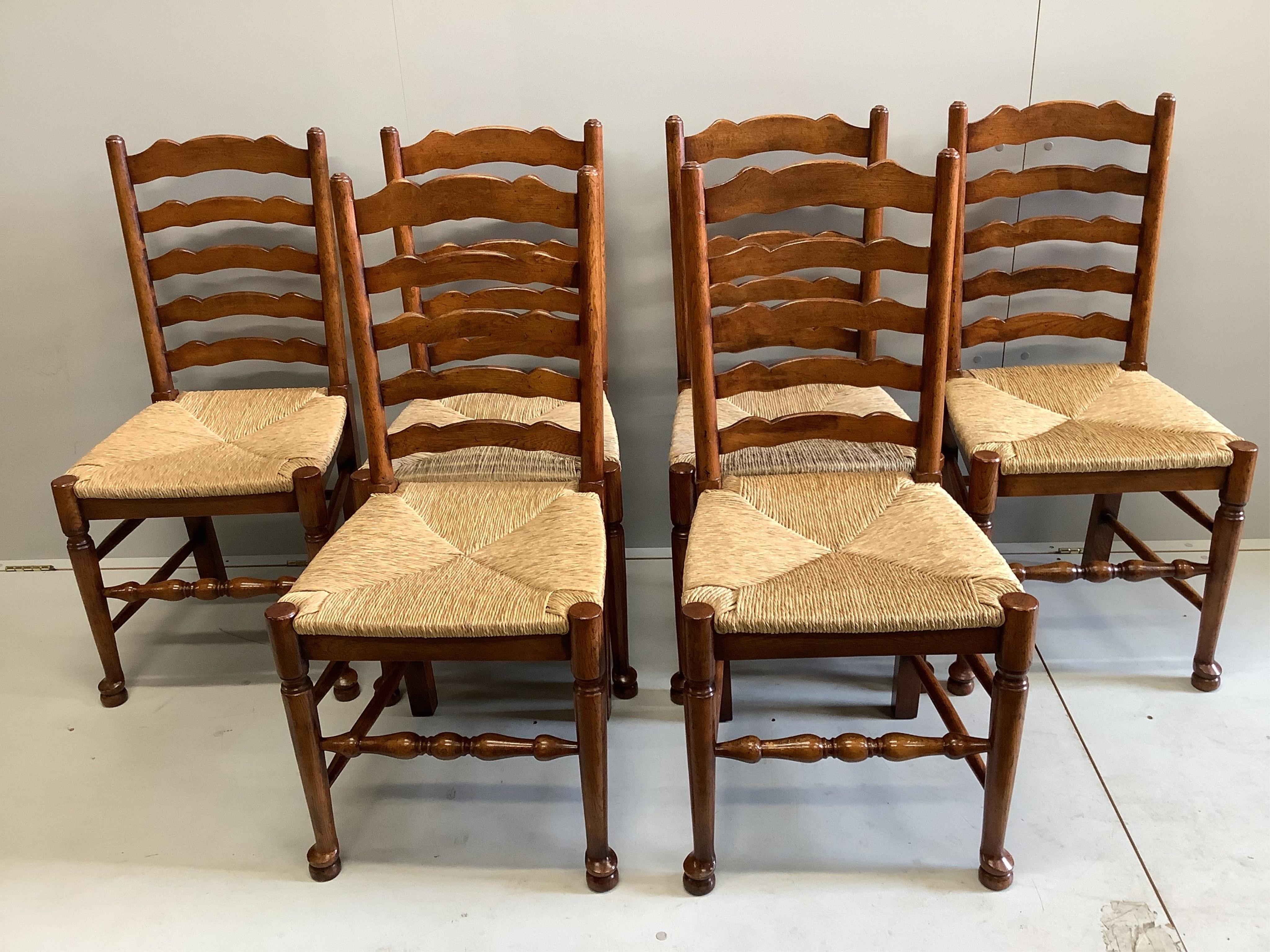 An 18th century style rectangular oak refectory dining table with cleated planked top on square tapered legs, width 213cm, depth 91cm, height 75cm together with a set of six oak rush seat ladderback dining chairs